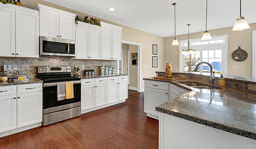 Large elegant medium tone wood floor eat-in kitchen photo in Other with a double-bowl sink, white cabinets, granite countertops, gray backsplash, brick backsplash, stainless steel appliances and an island