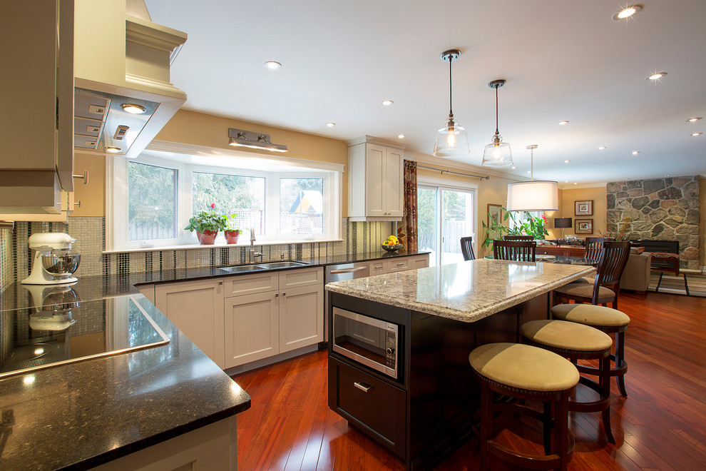 Example of a large transitional l-shaped dark wood floor open concept kitchen design in Toronto with a double-bowl sink, recessed-panel cabinets, white cabinets, metallic backsplash, mosaic tile backsplash, stainless steel appliances, an island and quartz countertops