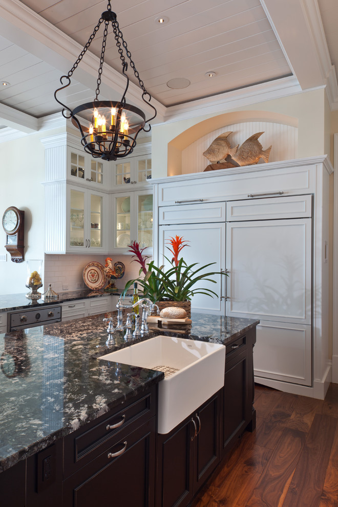 Elegant kitchen photo in Tampa with a farmhouse sink, recessed-panel cabinets, white cabinets, granite countertops, white backsplash, subway tile backsplash and paneled appliances