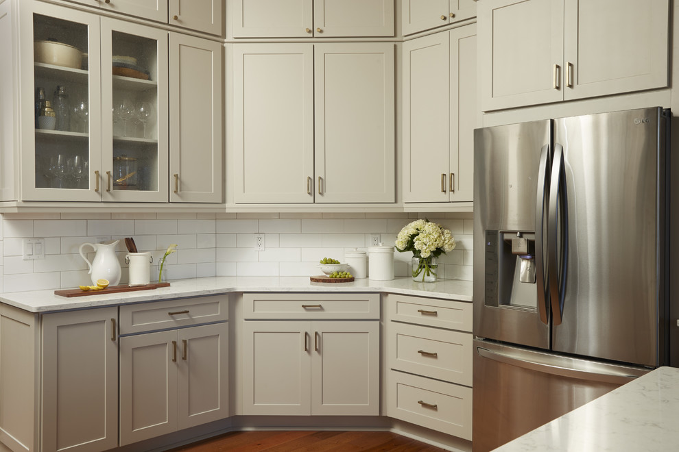Inspiration for a medium sized traditional u-shaped enclosed kitchen in Atlanta with a belfast sink, shaker cabinets, grey cabinets, engineered stone countertops, white splashback, metro tiled splashback, stainless steel appliances, medium hardwood flooring, a breakfast bar, brown floors and white worktops.