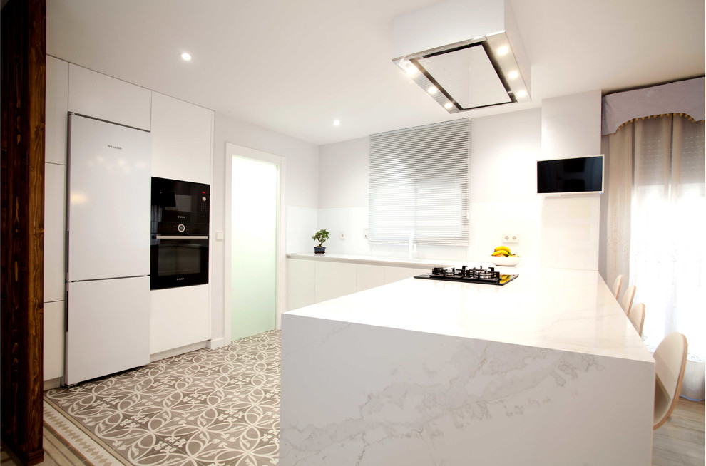 Example of a minimalist kitchen design in Valencia with quartz countertops, a peninsula and white countertops