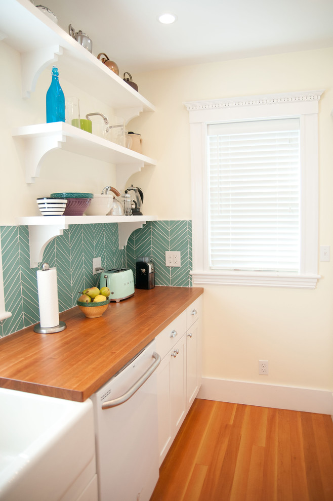 Inspiration for a mid-sized 1960s u-shaped medium tone wood floor eat-in kitchen remodel in Boston with a farmhouse sink, shaker cabinets, white cabinets, wood countertops, blue backsplash, glass tile backsplash, white appliances and a peninsula