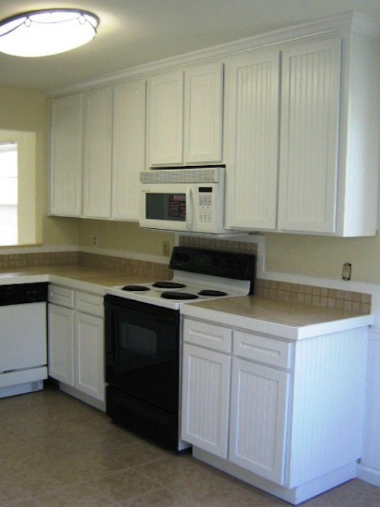 Exempel på ett stort kök, med släta luckor, brunt stänkskydd, svarta vitvaror, klinkergolv i keramik, vita skåp och kaklad bänkskiva