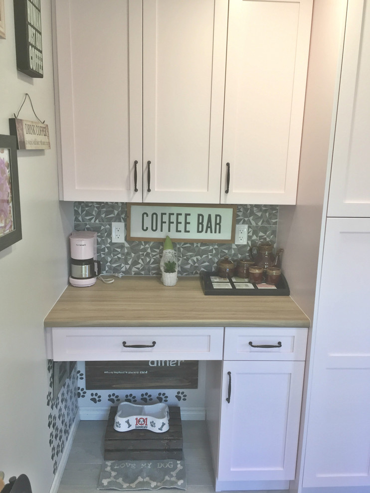 Inspiration for a medium sized vintage u-shaped kitchen pantry in Vancouver with a built-in sink, flat-panel cabinets, black cabinets, laminate countertops, grey splashback, mosaic tiled splashback, black appliances, vinyl flooring, no island, brown floors and brown worktops.