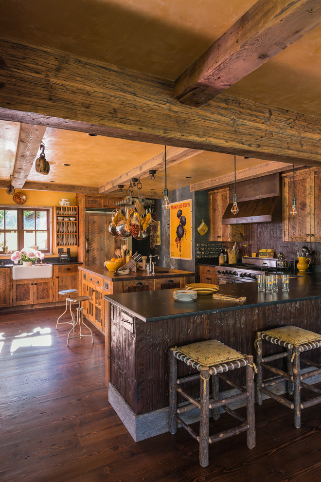 Rustik inredning av ett u-kök, med en rustik diskho, integrerade vitvaror, mörkt trägolv och en köksö