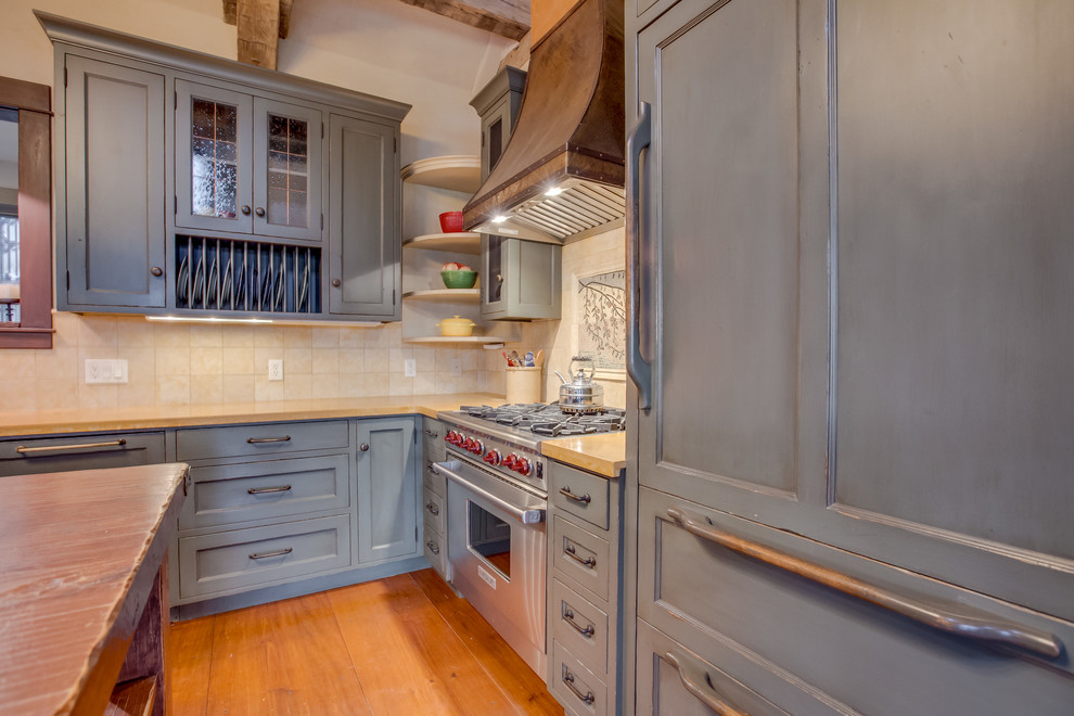 Modelo de cocina rústica con fregadero sobremueble, armarios con paneles empotrados, puertas de armario con efecto envejecido y electrodomésticos con paneles
