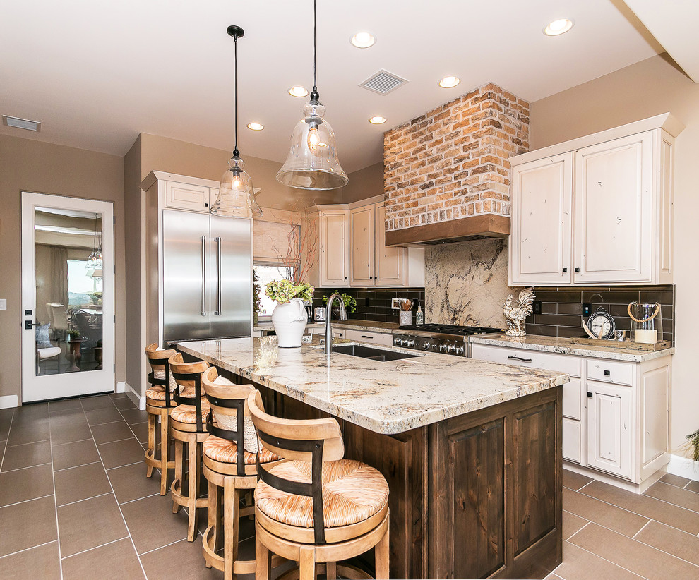 Eat-in kitchen - large southwestern l-shaped porcelain tile eat-in kitchen idea in Phoenix with an undermount sink, raised-panel cabinets, white cabinets, granite countertops, multicolored backsplash, stone tile backsplash, stainless steel appliances and an island