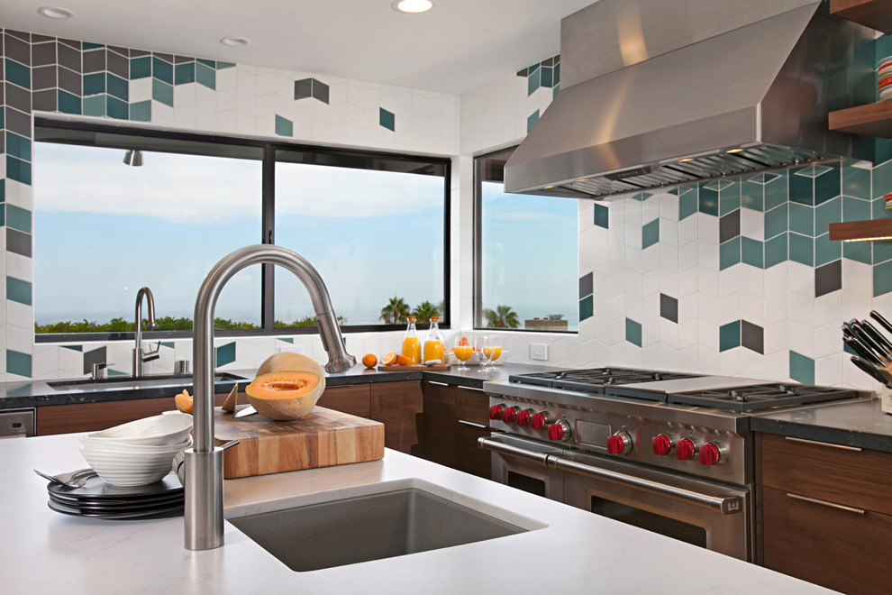 Geschlossene Moderne Küche in U-Form mit Unterbauwaschbecken, flächenbündigen Schrankfronten, dunklen Holzschränken, bunter Rückwand, Küchengeräten aus Edelstahl, hellem Holzboden, Kücheninsel und beigem Boden in San Diego