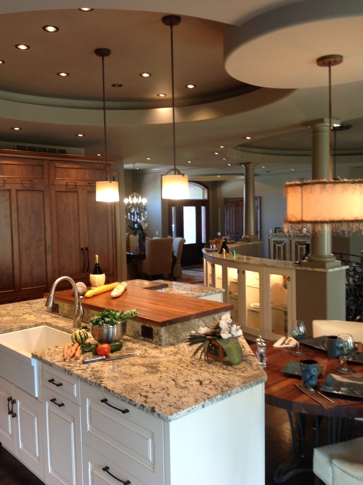 Bild på ett stort funkis flerfärgad flerfärgat l-kök, med en undermonterad diskho, luckor med infälld panel, vita skåp, granitbänkskiva, beige stänkskydd, stänkskydd i travertin, integrerade vitvaror, mörkt trägolv, en köksö och brunt golv