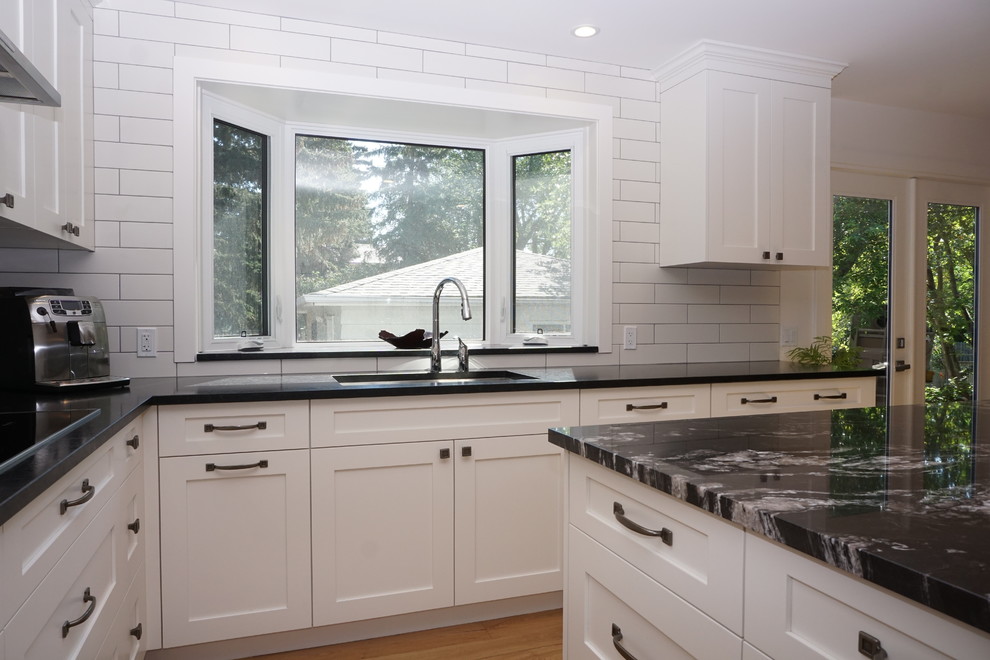 Esempio di una cucina chic di medie dimensioni con lavello sottopiano, ante in stile shaker, ante bianche, top in granito, paraspruzzi bianco, parquet chiaro e top nero