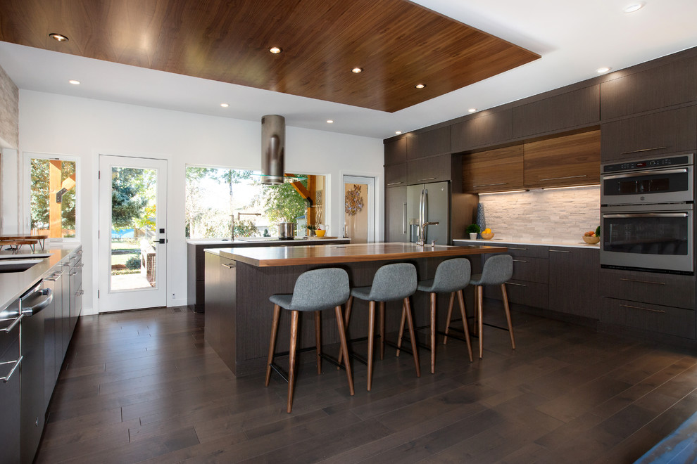 Inspiration for a large modern u-shaped medium tone wood floor kitchen remodel in Denver with flat-panel cabinets, quartz countertops, stainless steel appliances, an island and white countertops