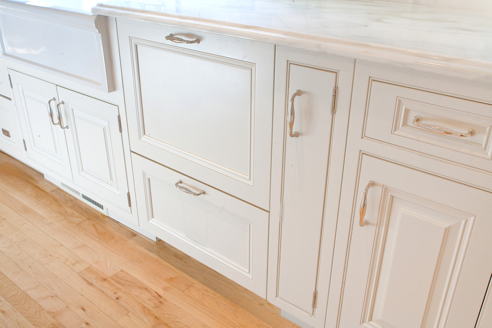 Diseño de cocina comedor clásica con fregadero sobremueble, armarios con rebordes decorativos, puertas de armario blancas y electrodomésticos con paneles