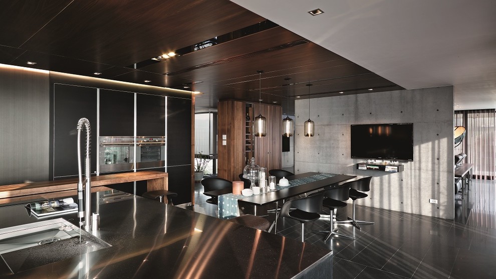Ejemplo de cocina comedor actual con armarios con paneles lisos, puertas de armario negras, electrodomésticos de acero inoxidable y suelo negro