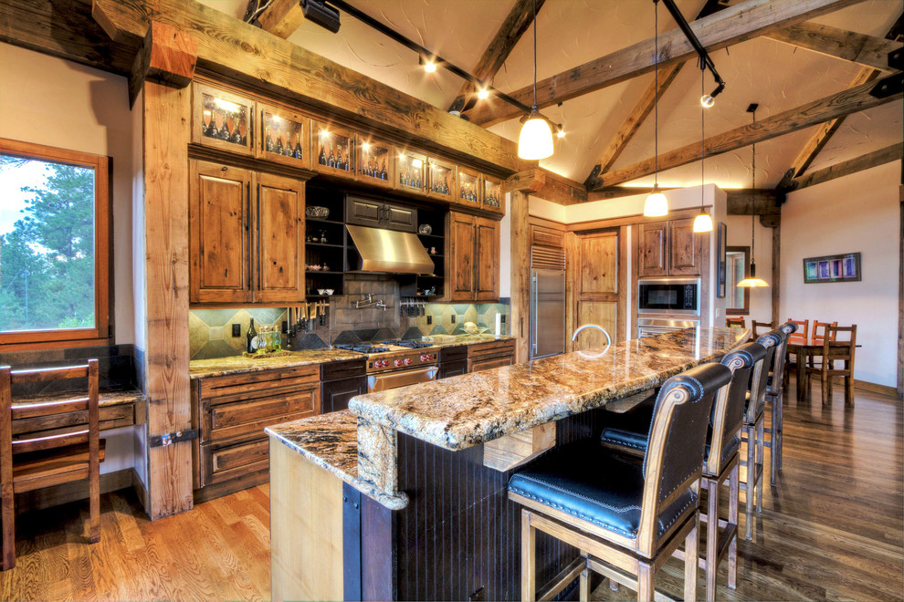 Large mountain style l-shaped medium tone wood floor and brown floor open concept kitchen photo in Denver with raised-panel cabinets, medium tone wood cabinets, granite countertops, gray backsplash, ceramic backsplash, stainless steel appliances, an island and brown countertops