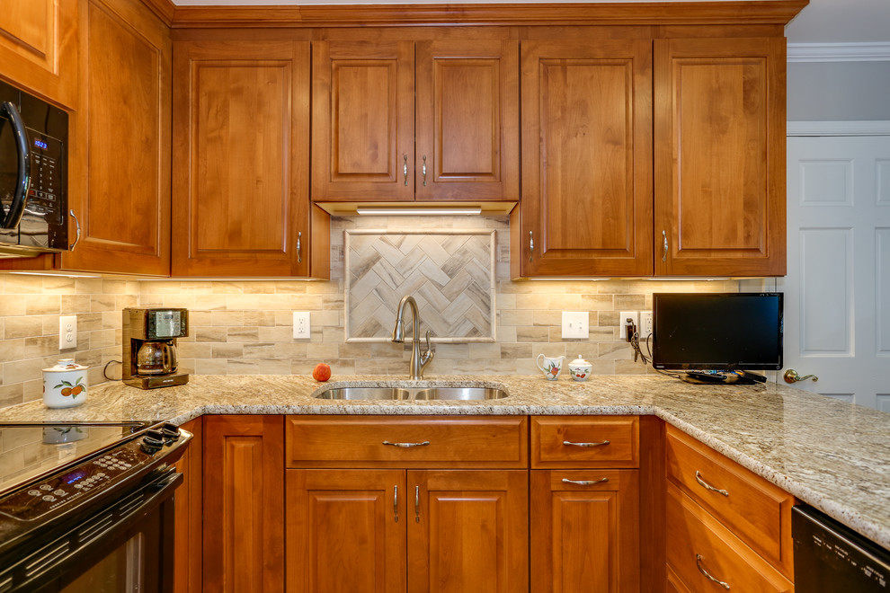 Klassisk inredning av ett mellanstort beige beige kök, med en dubbel diskho, luckor med upphöjd panel, skåp i mellenmörkt trä, granitbänkskiva, beige stänkskydd, svarta vitvaror, mellanmörkt trägolv och flerfärgat golv