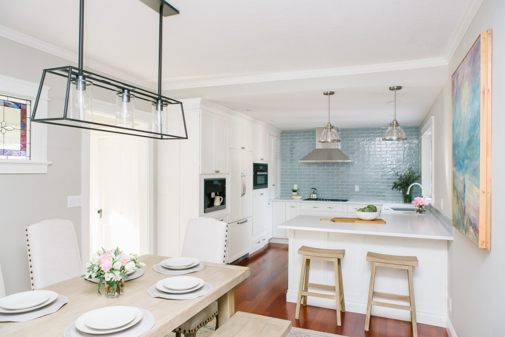 Klassisk inredning av ett litet vit vitt kök, med en undermonterad diskho, skåp i shakerstil, vita skåp, bänkskiva i kvarts, blått stänkskydd, stänkskydd i keramik, rostfria vitvaror, mellanmörkt trägolv, en halv köksö och rött golv