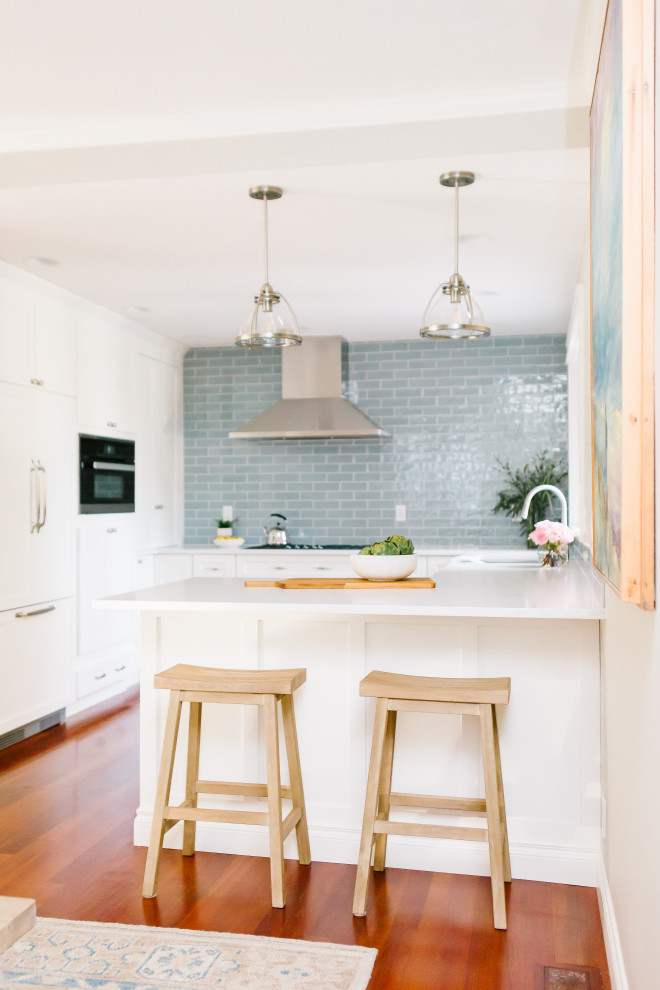 Diseño de cocina clásica renovada pequeña con fregadero bajoencimera, armarios estilo shaker, puertas de armario blancas, encimera de cuarzo compacto, salpicadero azul, salpicadero de azulejos de cerámica, electrodomésticos de acero inoxidable, suelo de madera en tonos medios, península, suelo rojo y encimeras blancas