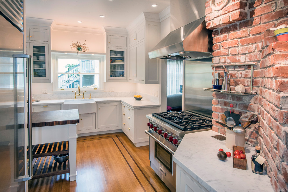 Idéer för avskilda, mellanstora amerikanska vitt l-kök, med en rustik diskho, luckor med profilerade fronter, vita skåp, marmorbänkskiva, rostfria vitvaror, mellanmörkt trägolv, en köksö och brunt golv