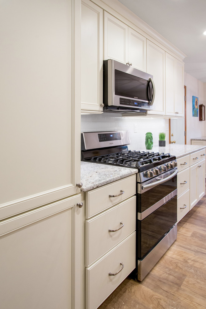 Modern inredning av ett mellanstort flerfärgad flerfärgat kök, med en undermonterad diskho, luckor med infälld panel, vita skåp, granitbänkskiva, vitt stänkskydd, stänkskydd i keramik, rostfria vitvaror, vinylgolv och beiget golv