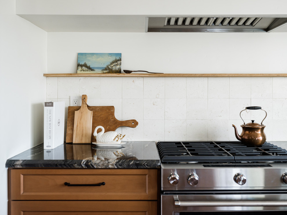 Idéer för att renovera ett mellanstort vintage svart svart kök, med en undermonterad diskho, luckor med upphöjd panel, skåp i ljust trä, granitbänkskiva, beige stänkskydd, stänkskydd i kalk, rostfria vitvaror, ljust trägolv, en köksö och beiget golv