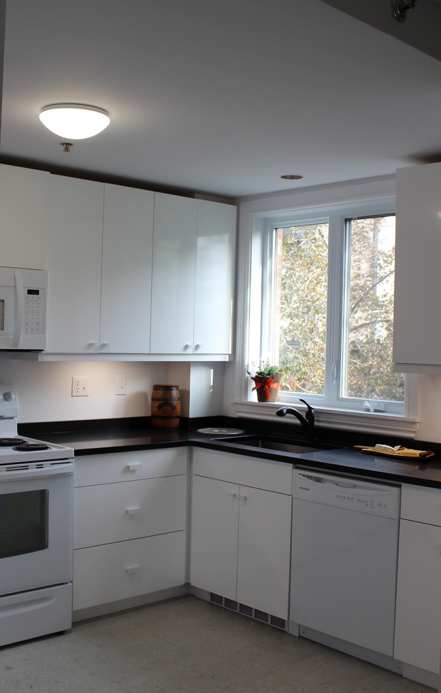 Immagine di una cucina a L moderna chiusa e di medie dimensioni con ante lisce, ante bianche, top in superficie solida, elettrodomestici bianchi, pavimento in gres porcellanato e pavimento grigio