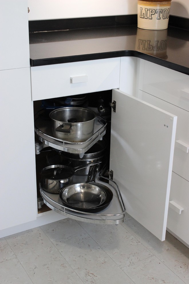 Inredning av ett modernt avskilt, mellanstort l-kök, med släta luckor, vita skåp, bänkskiva i koppar, vita vitvaror, klinkergolv i porslin och grått golv