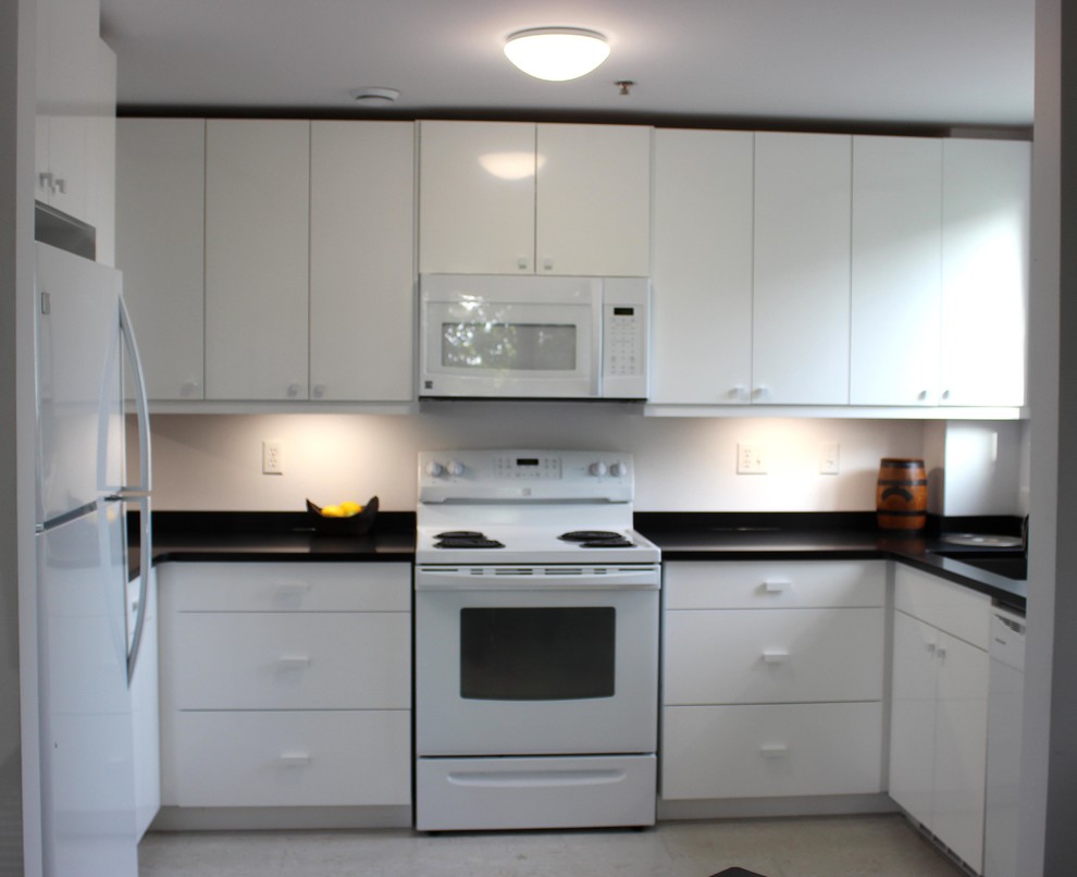 Immagine di una cucina a L minimalista chiusa e di medie dimensioni con ante lisce, ante bianche, top in superficie solida, elettrodomestici bianchi, pavimento in gres porcellanato e pavimento grigio