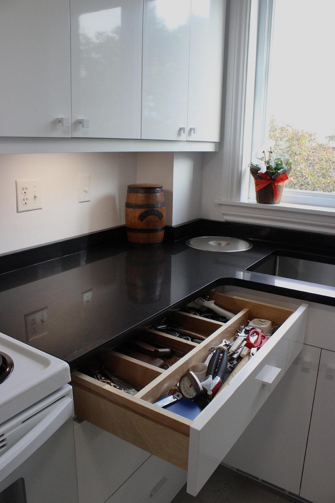 Immagine di una cucina a L minimalista chiusa e di medie dimensioni con ante lisce, ante bianche, top in superficie solida, elettrodomestici bianchi, pavimento in gres porcellanato e pavimento grigio