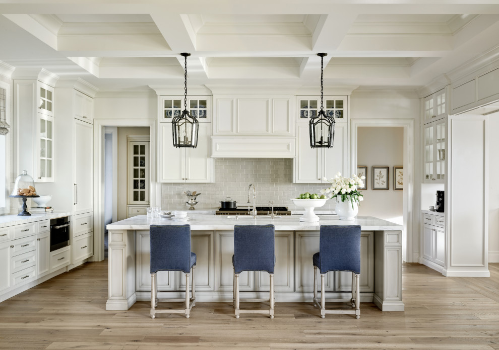 Large tuscan u-shaped medium tone wood floor, beige floor and coffered ceiling kitchen photo in Phoenix with an undermount sink, recessed-panel cabinets, white cabinets, gray backsplash, paneled appliances, an island and gray countertops