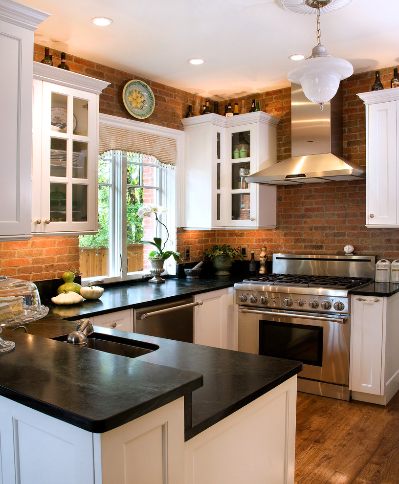 Example of a small transitional u-shaped dark wood floor eat-in kitchen design in Denver with a single-bowl sink, glass-front cabinets, white cabinets, soapstone countertops, black backsplash, stone slab backsplash and stainless steel appliances