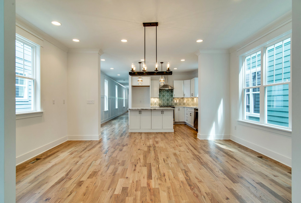 Klassisk inredning av ett mellanstort grå linjärt grått kök, med en enkel diskho, skåp i shakerstil, vita skåp, marmorbänkskiva, blått stänkskydd, stänkskydd i cementkakel, rostfria vitvaror, ljust trägolv, en köksö och beiget golv