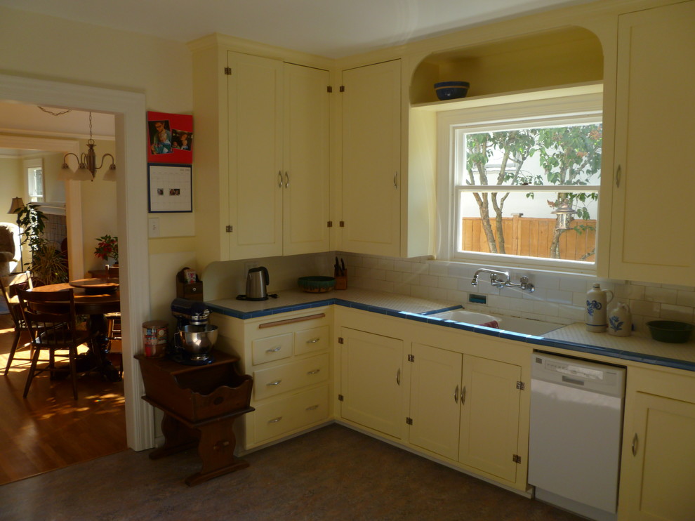 Design ideas for a medium sized classic l-shaped kitchen in Seattle with a submerged sink, shaker cabinets, yellow cabinets, tile countertops, white splashback, ceramic splashback, white appliances and no island.