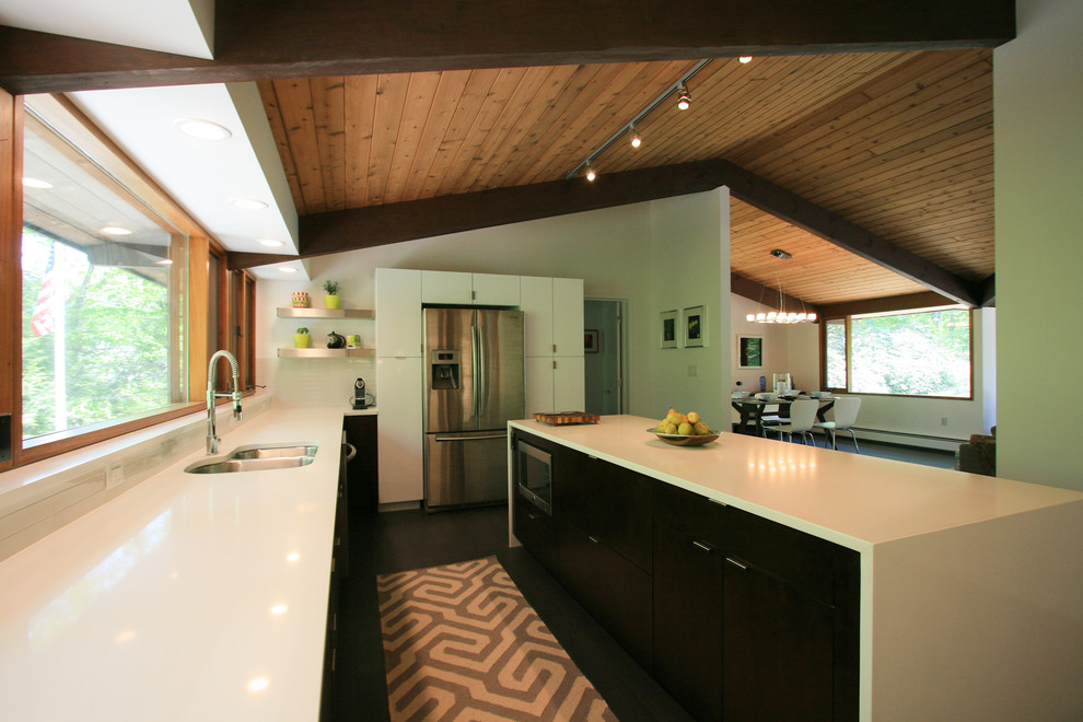 This is an example of a contemporary u-shaped open plan kitchen in Boston with a submerged sink, flat-panel cabinets, dark wood cabinets, engineered stone countertops, white splashback, ceramic splashback, stainless steel appliances, dark hardwood flooring and an island.