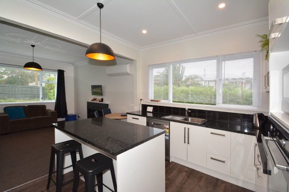 Kleine Moderne Küche mit weißen Schränken, Küchenrückwand in Schwarz, Rückwand aus Keramikfliesen und Kücheninsel in Dunedin