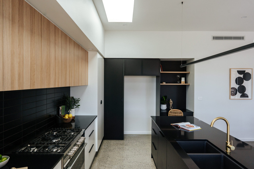 Inredning av ett modernt mellanstort svart svart kök, med en undermonterad diskho, släta luckor, svarta skåp, bänkskiva i kvarts, svart stänkskydd, stänkskydd i keramik, rostfria vitvaror, betonggolv, en köksö och grått golv