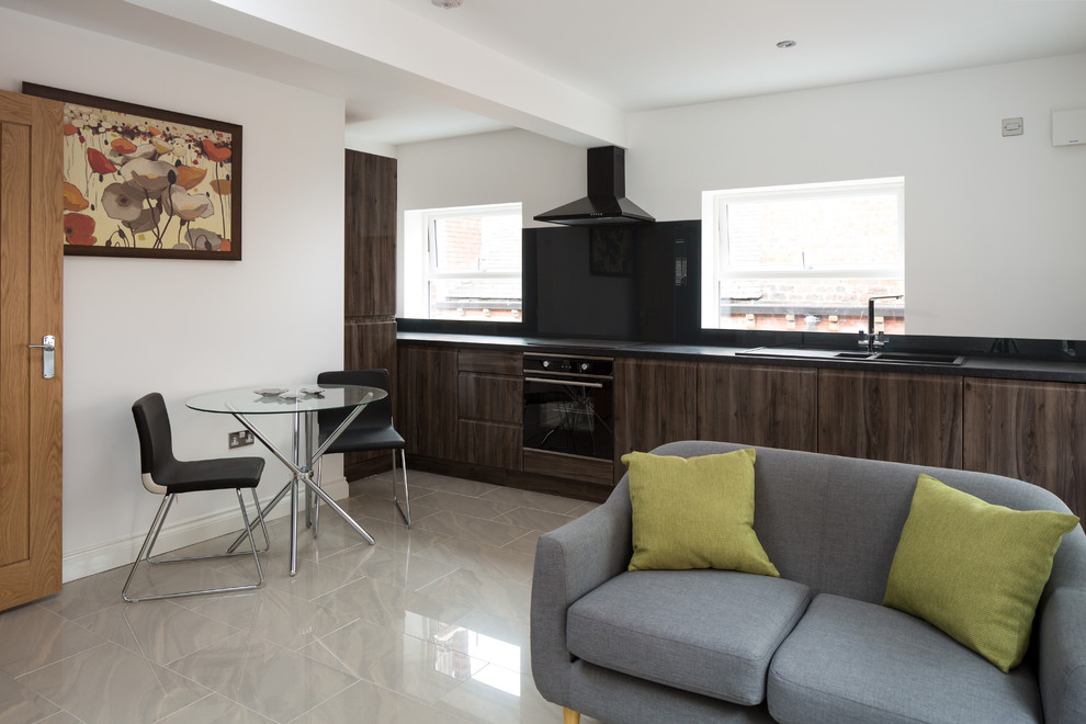 This is an example of a small contemporary l-shaped open plan kitchen in Other with a single-bowl sink, flat-panel cabinets, dark wood cabinets, granite worktops, black splashback, black appliances, marble flooring and no island.