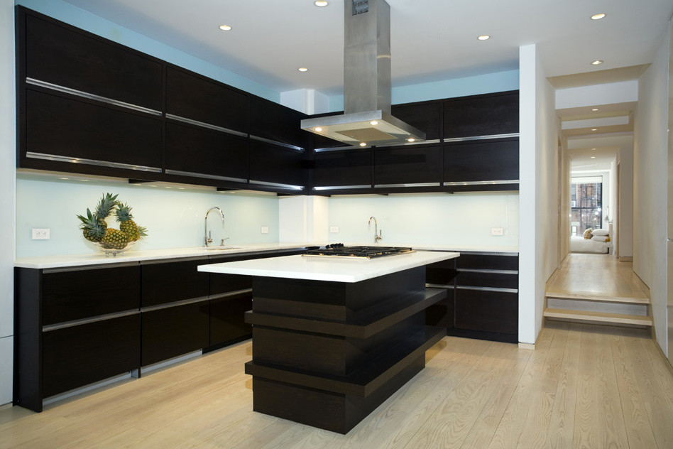 Inredning av ett modernt stort kök, med en dubbel diskho, släta luckor, svarta skåp, bänkskiva i koppar, vitt stänkskydd, rostfria vitvaror, ljust trägolv, en köksö och blått golv