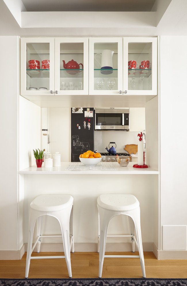 Diseño de cocina clásica renovada de tamaño medio con puertas de armario blancas, fregadero bajoencimera, encimera de acrílico, salpicadero blanco, electrodomésticos blancos y suelo de madera clara