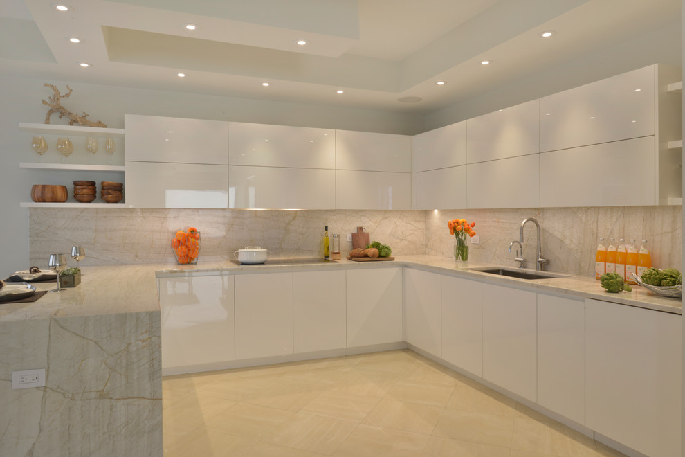 Inredning av ett modernt stort kök, med en undermonterad diskho, släta luckor, vita skåp, marmorbänkskiva, beige stänkskydd, vita vitvaror, marmorgolv och en halv köksö