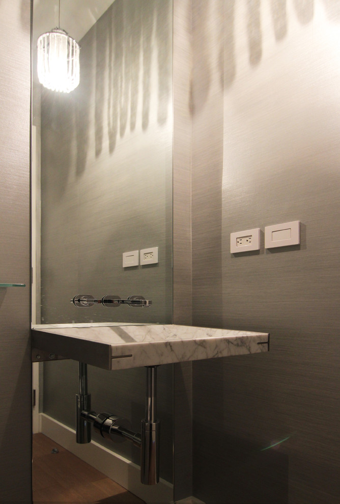 Inspiration pour un petit WC et toilettes minimaliste avec un lavabo suspendu, un placard sans porte, un plan de toilette en marbre, WC à poser, un mur gris et parquet clair.