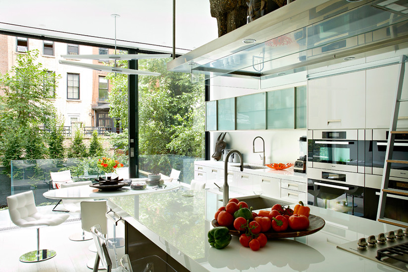 Exempel på ett stort modernt linjärt kök och matrum, med en undermonterad diskho, släta luckor, vita skåp, bänkskiva i kvarts, rostfria vitvaror, ljust trägolv och en köksö