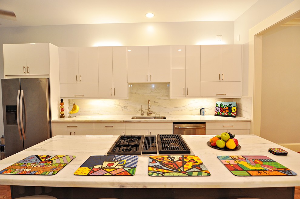 Exempel på ett mellanstort modernt vit vitt kök, med en undermonterad diskho, släta luckor, vita skåp, bänkskiva i kvartsit, vitt stänkskydd, rostfria vitvaror, laminatgolv, en köksö och brunt golv