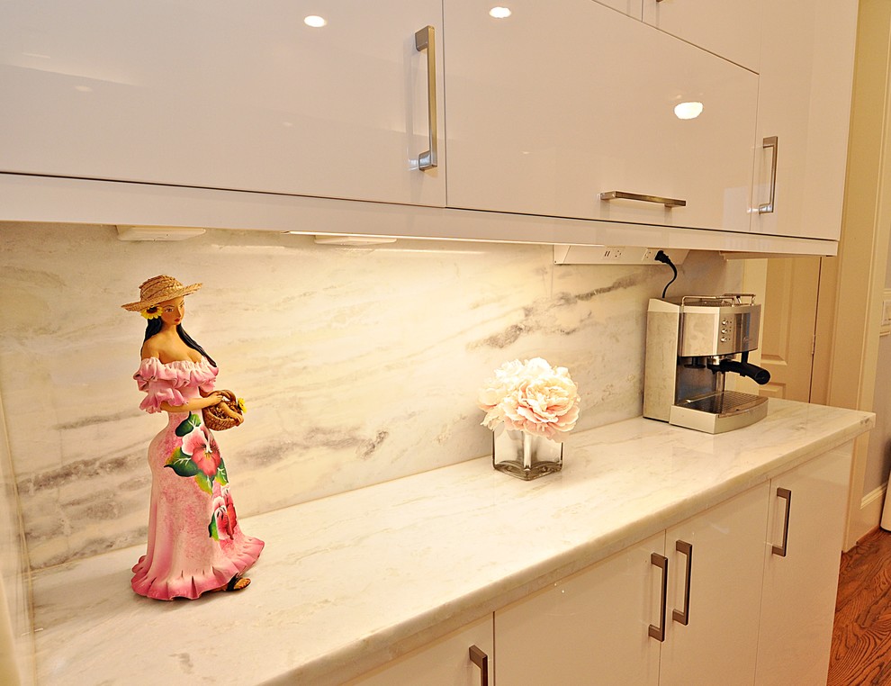 Bild på ett mellanstort funkis vit vitt kök, med en undermonterad diskho, släta luckor, vita skåp, bänkskiva i kvartsit, vitt stänkskydd, rostfria vitvaror, laminatgolv, en köksö och brunt golv
