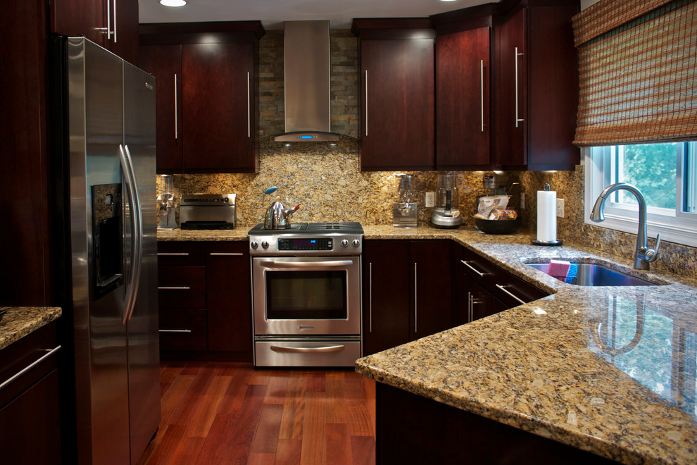 Foto di una cucina ad U design di medie dimensioni con lavello sottopiano, ante in legno bruno, top in granito, paraspruzzi marrone, elettrodomestici in acciaio inossidabile e penisola