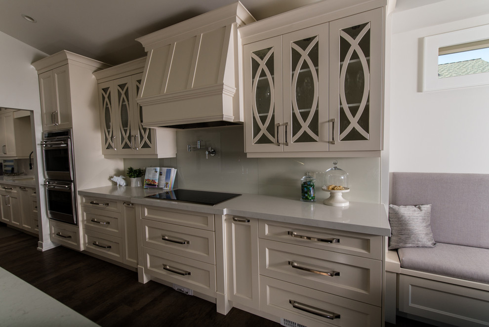 Example of a trendy l-shaped open concept kitchen design in Vancouver with an undermount sink, glass-front cabinets, white cabinets, quartz countertops, white backsplash, glass sheet backsplash and paneled appliances