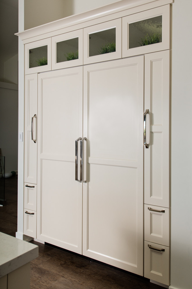Idée de décoration pour une cuisine américaine encastrable design en L avec un placard à porte shaker et des portes de placard blanches.
