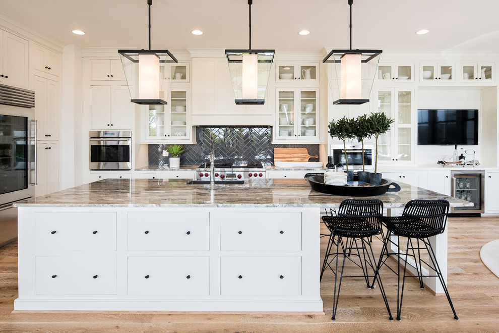ワシントンD.C.にあるトランジショナルスタイルのおしゃれなアイランドキッチン (ガラス扉のキャビネット、黒いキッチンパネル、シルバーの調理設備、無垢フローリング) の写真