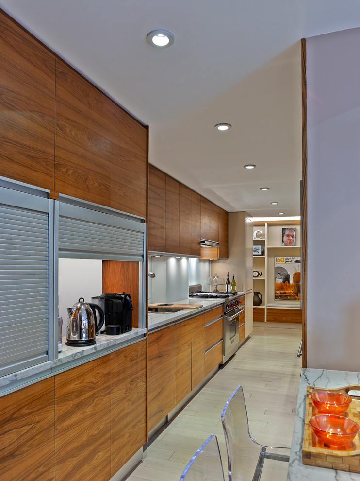 This is an example of a small contemporary galley kitchen/diner in New York with a built-in sink, flat-panel cabinets, medium wood cabinets and stainless steel appliances.