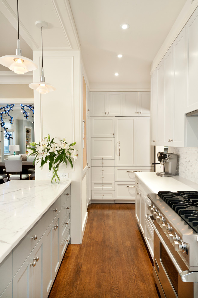 Small transitional u-shaped medium tone wood floor and brown floor open concept kitchen photo in New York with gray backsplash, paneled appliances, an undermount sink, marble countertops, stone tile backsplash, a peninsula, shaker cabinets and white cabinets