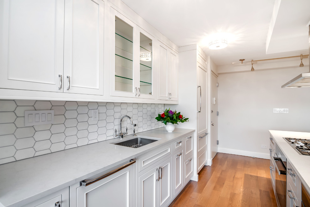 Small elegant galley medium tone wood floor eat-in kitchen photo in New York with an undermount sink, beaded inset cabinets, white cabinets, quartz countertops, white backsplash, stone tile backsplash, stainless steel appliances and an island